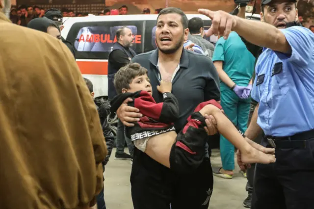 A man carrying a child arrives at Nasser Hospital