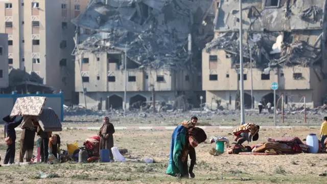 Palestinians carry their belongings following Israeli strikes on residential buildings at the Qatari-funded Hamad City,