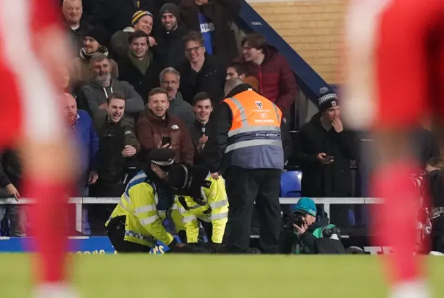 A spectator is tackled by police at AFC Wimbledon v Ramsgate after invading the pitch