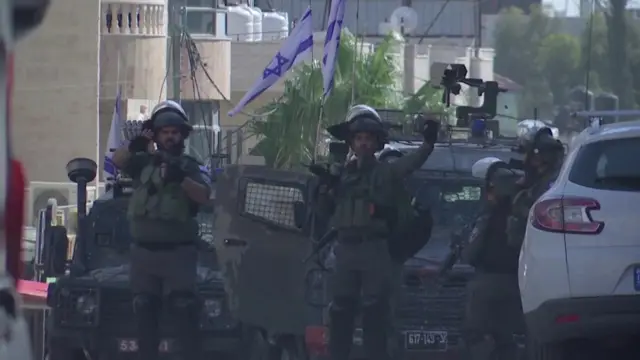 IDF solders in combat gear during the raid, standing in front of two armoured vehicles