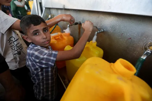 A boy filling a bright yellow container with water