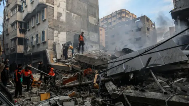 Palestinian citizens inspect the destruction caused by air strikes on their homes on 4 December 2023,