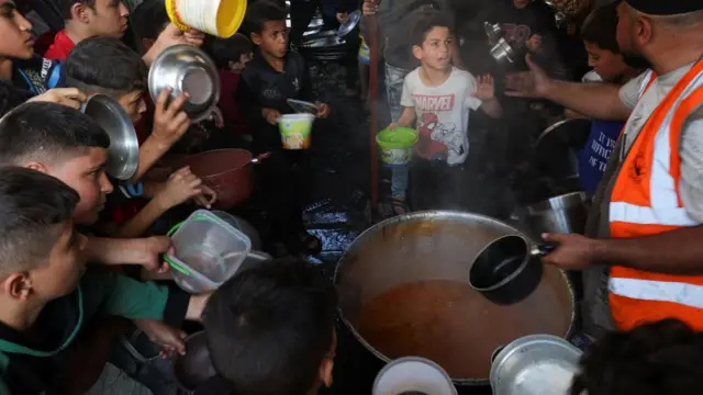 Palestinians pictured getting their share of charity food offered by volunteer, 2 December