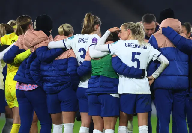 England players debrief on the pitch after the game.