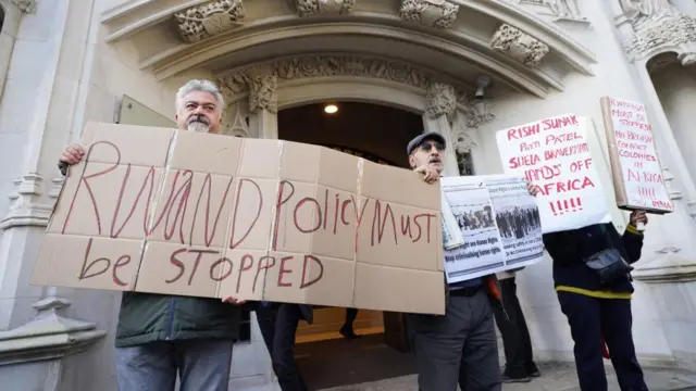 Protesters with placards demonstrate against the government's Rwanda policy