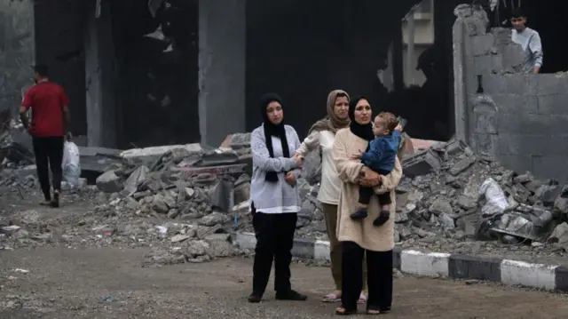 Palestinians pictured making their way through the rubble following strikes on Deir al-Balah