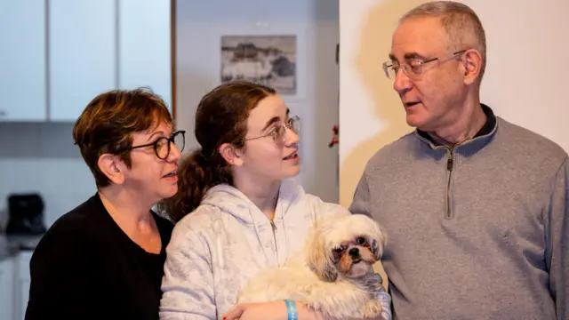 Mia Leimberg, 17, released from captivity after being taken hostage by the Palestinian Islamist group Hamas in the Gaza Strip with her mother Gabriela and her dog Bella, holds the dog in her arms as she stands with her mother and father, Moshe, at their home in Jerusalem, December 5, 2023.