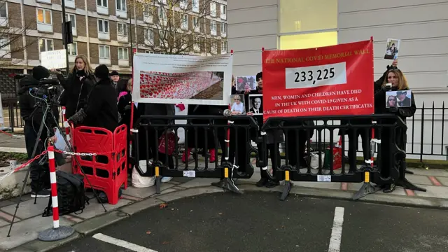 Protestors gather outside Covid inquiry, holding banners of Covid Memorial Wall and saying "233,225" people have died with Covid in the UK