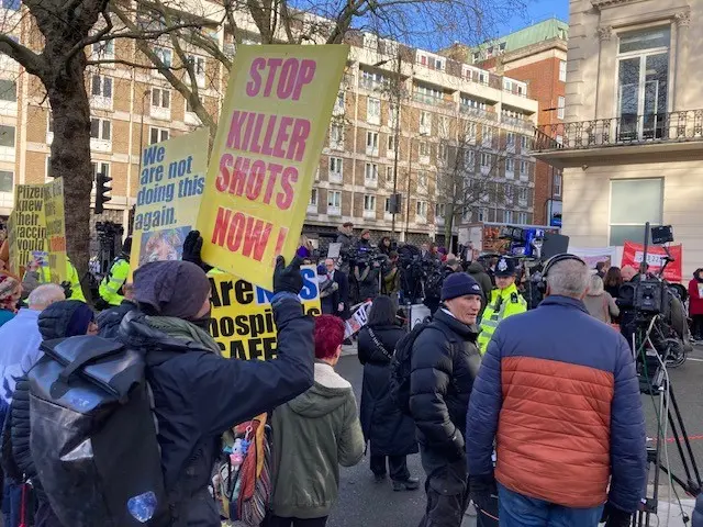 Anti-vaccine protestors stand with placards outside the inquiry