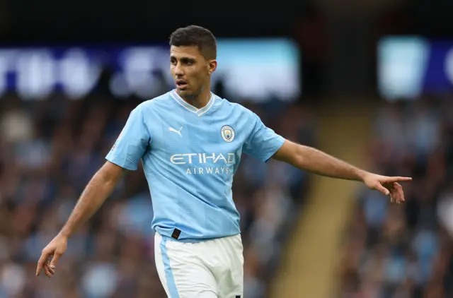 Rodri points instructions to a teammate with his left hand.