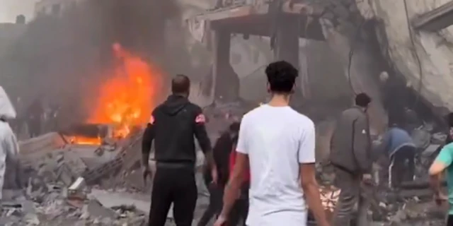 Aftermath of strike in town of Deir al-Balah in Gaza, showing flames and damaged buidlingsed buildings