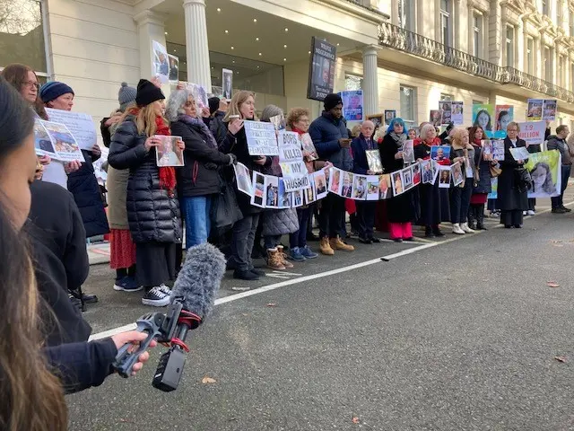 Bereaved family members hold signs outside the inquiry