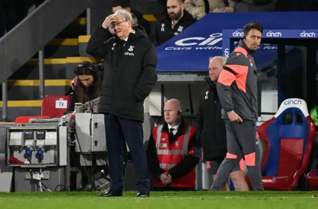 Hodgson holds his head while standing in front of the dugout.