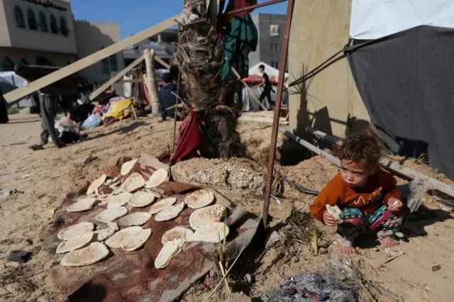 A child eats outside a tent, as displaced Palestinians shelter in a camp in Rafah