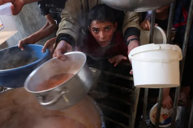 Palestinians pictured getting their share of charity food offered by volunteers