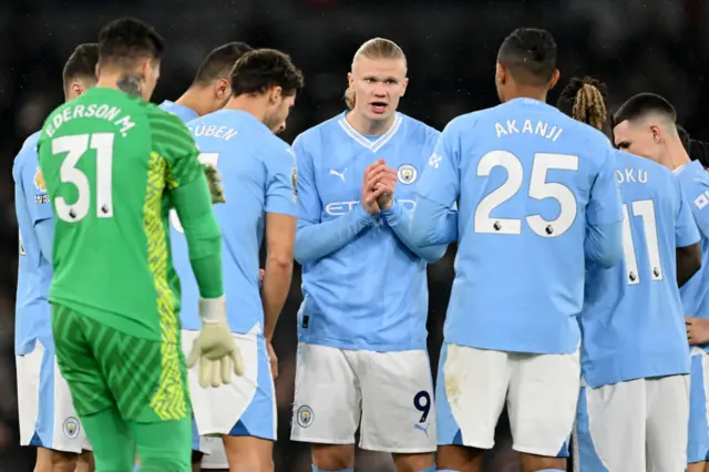 Man City players huddle as Haaland addresses the group.