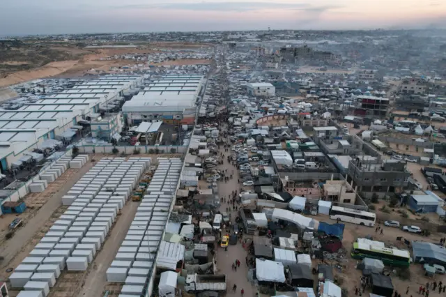 An aerial picture shows displaced Palestinians setting up camp near warehouses affiliated in the UN in Rafah, 7 December 2023