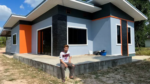 Anucha sitting on ledge outside Thai family home