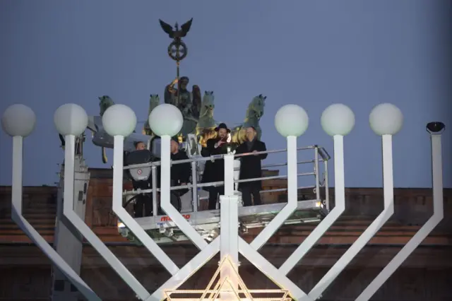 German Chancellor Olaf Scholz (R) lights a candle next to Chairman of the Jewish Education Center Chabad Rabbi Yehuda Teichta