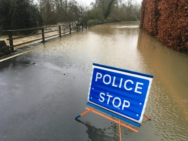 A police stop sign in front of a flooded road