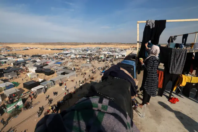 A woman hanging clothes over a Palestinian refugee camp