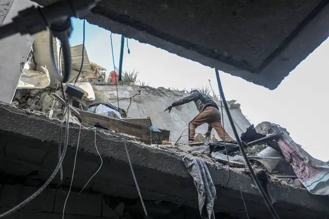 A person clears debris among rubble in Rafah on 7 December