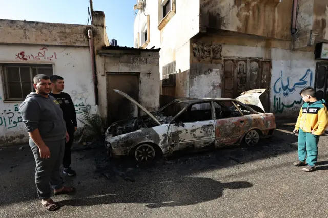 Palestinians check a burnt car in the village of al-Fara, in the occupied West Bank, following an Israeli raid on December 8, 2023. Israeli forces shot dead six Palestinians on December 8, 2023 in a raid on a refugee camp in the north of the Israeli-occupied West Bank, the Palestinian health ministry said. The ministry, updating an earlier toll of five dead, did not identify them but said they had been killed "by bullets from the occupation (Israel) in the Al-Fara refugee camp" near Tubas. (Photo by Zain JAAFAR / AFP) (Photo by ZAIN JAAFAR/AFP via Getty Images)