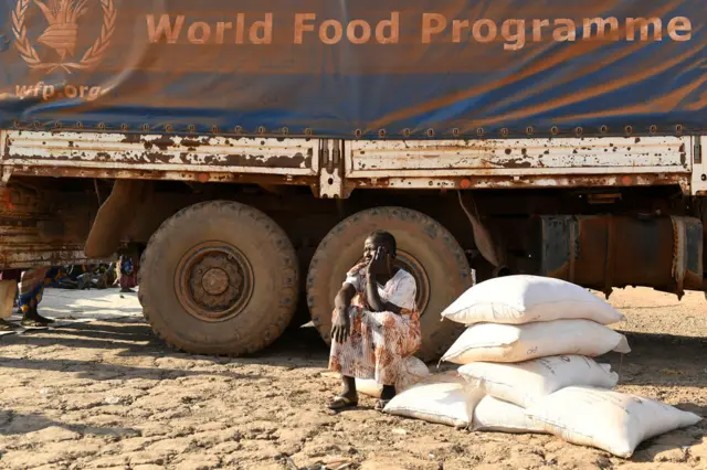 An internally displaced women sits next to a World Food Programme truck during a food distribution in Bentiu on February 6, 2023.