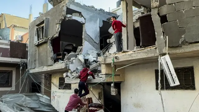 Palestinians inspect damage after a building was hit by a strike