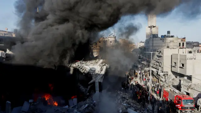 Fire burns and smoke billows at a destroyed house