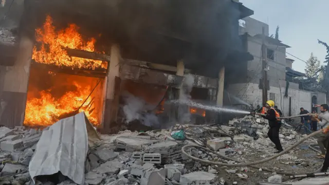 A Palestinian firefighter works to extinguish a fire in a house after an Israeli strike