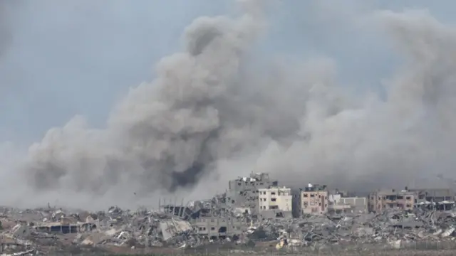 Smoke rises over buildings - many of them decimated - in Gaza City