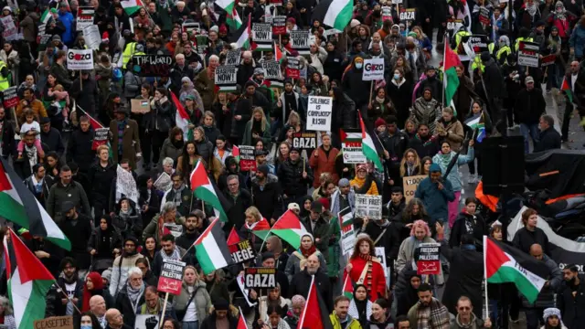 A crowd of protesters - many of them with pro-Palestinian signs - walk through London