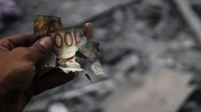 File image of a hand holding a burnt banknote