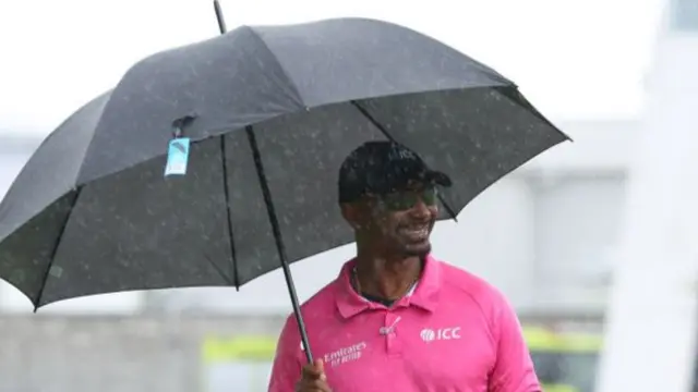 Reserve Umpire Gregory Brathwaite leaves the field of play as rain falls before the third ODI match between West Indies and England at the Kensington Oval