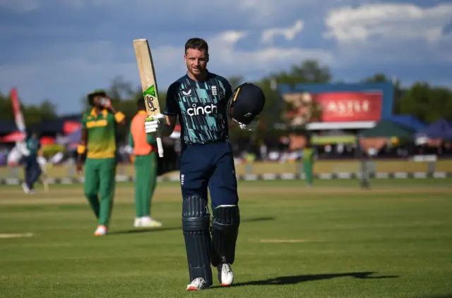 Jos Buttler walking off the pitch holding his bat in the air