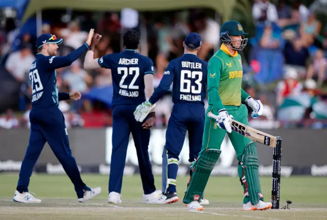 South Africa's Rassie van der Dussen (R) walks back to the pavilion after his dismissal by England's Jofra Archer (C/#22) during the third one day international (ODI) cricket match between South Africa and England at Mangaung Oval