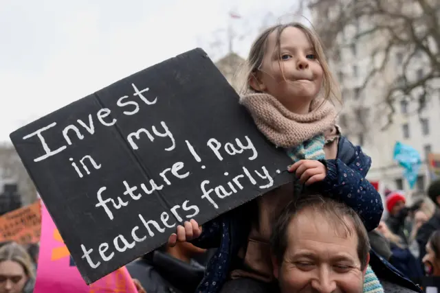 Girl on man's shoulders with placard