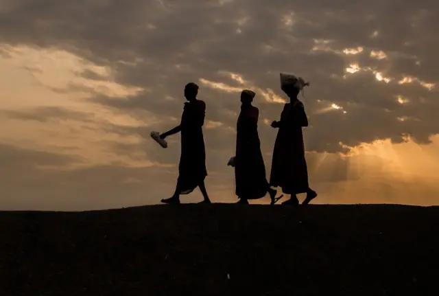 Internally displaced women walk to a food distribution in the early morning at the Protection of Civilian site (PoC) in Bentiu, South Sudan, on February 13, 2018