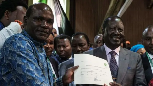 Raila Odinga (L) poses with the certificate of registration as presidential candidate from Wafula Chebukati (L) ahead of last August election