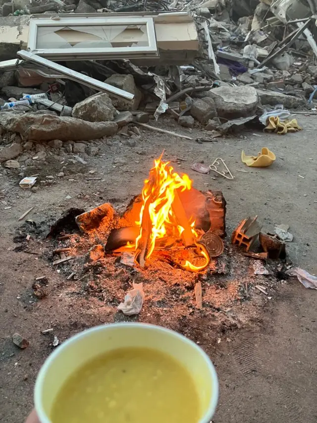 A cup of soup held near a fire