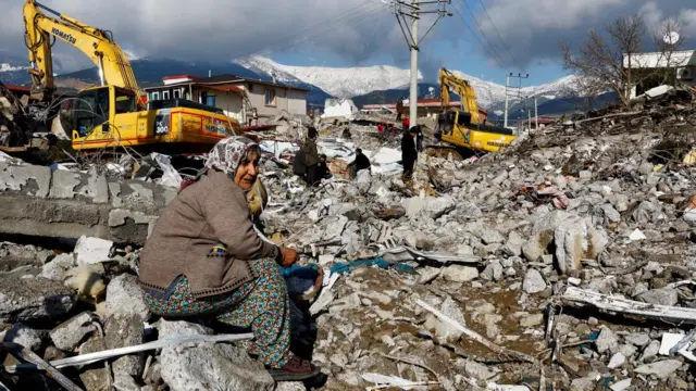 A woman sits amidst rubble following an earthquake in Gaziantep, Turkey