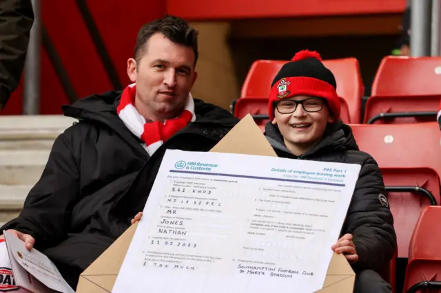 A young Southampton fan holding a sign in protest against the club's manager Nathan Jones