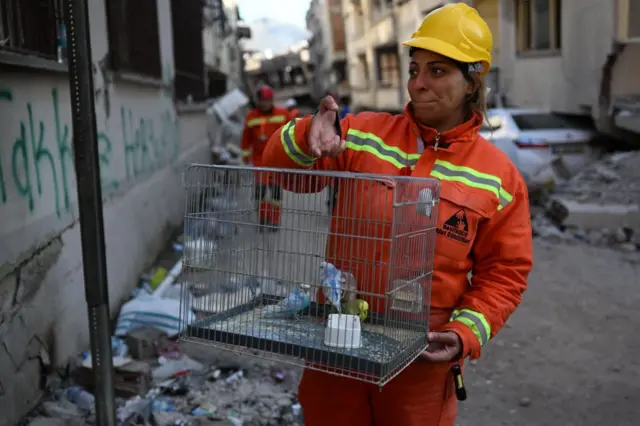 A emergency worker holds a cage with birds she found in a building in Hatay, Turkey