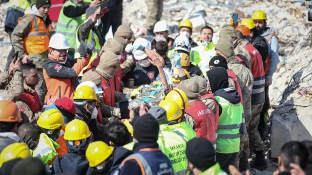 Rescuers surround a boy being stretchered out of a collapsed building in Hatay, Turkey