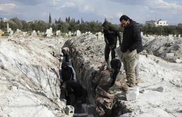 Volunteers prepare graves for earthquake victims in the rebel-held town of Jandaris, Syria, on Friday