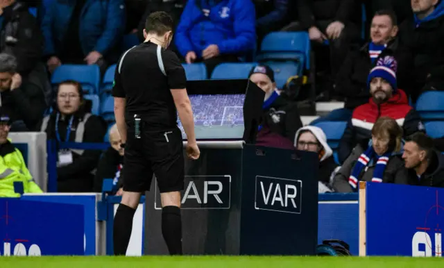 Referee David Munro watches replays before giving the spot-kick