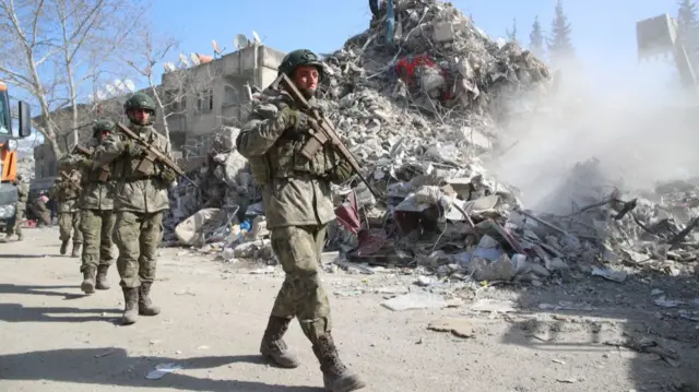 Soldiers march past collapsed buildings in Kahramanmaras