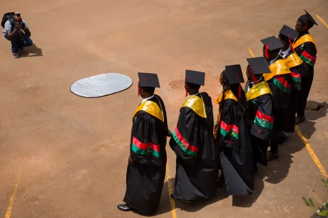 University graduates pose for a photographer