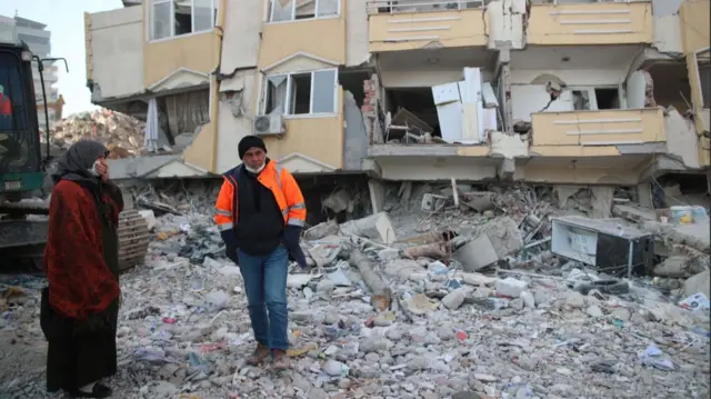 Relatives wait next to collapsed buildings in Kahramanmaras